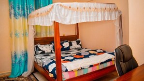 A single bed with a canopy, a wooden headboard, and a colorful bedspread. - Latahzan Guest House (Moyale)