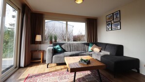 A modern living room with a grey sectional sofa, a wooden coffee table, and a patterned rug. - Chalet Near Golf Course and sea Beach (Hollum)