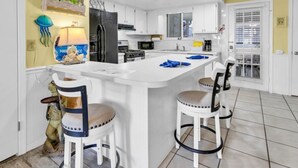 Cozinha moderna com armários brancos, uma ilha central e banquetas de bar.