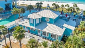 Um hotel com piscina, vista para a praia e um edifício azul com um letreiro.