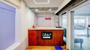 A reception desk with a sign indicating it is company-serviced, a ceiling with recessed lighting, and a view of the outside through a glass door.