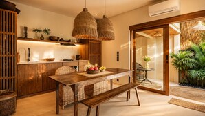 Eine moderne Küche mit Holzschränken, einem Esstisch mit Korbstühlen und einem großen Fenster.