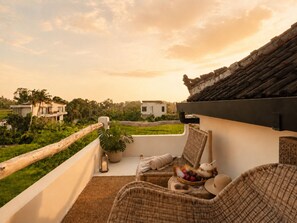 A balcony with wicker furniture, a potted plant, and a bowl of fruit. - Rice Field Villa with Rooftop Jacuzzi (Canggu)