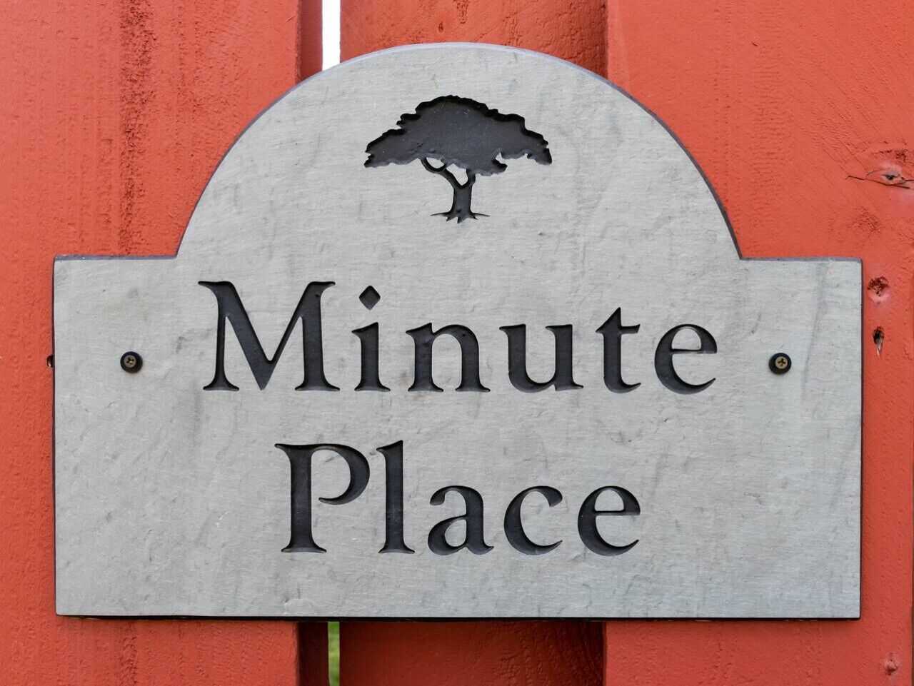 A sign with the text "Minute Place" and a silhouette of a tree above it.