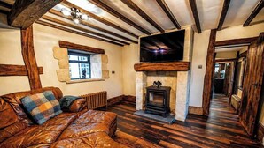 Una habitación con sofá de cuero, chimenea de piedra, vigas de madera y pared de piedra.
