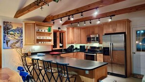 Une cuisine moderne avec des meubles en bois, un grand îlot central et des appareils électroménagers en acier inoxydable.