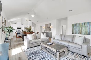 Un salon moderne comprenant un canapé, une table basse et un coin repas avec des chaises et une table.