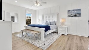 Un dormitorio con una cama grande, un banco, una mesita de noche y un ventilador de techo.