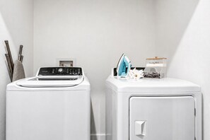 Un espace buanderie comprenant deux machines à laver blanches et un étendoir.
