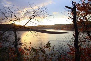 A lake surrounded by trees with a sunset in the background.