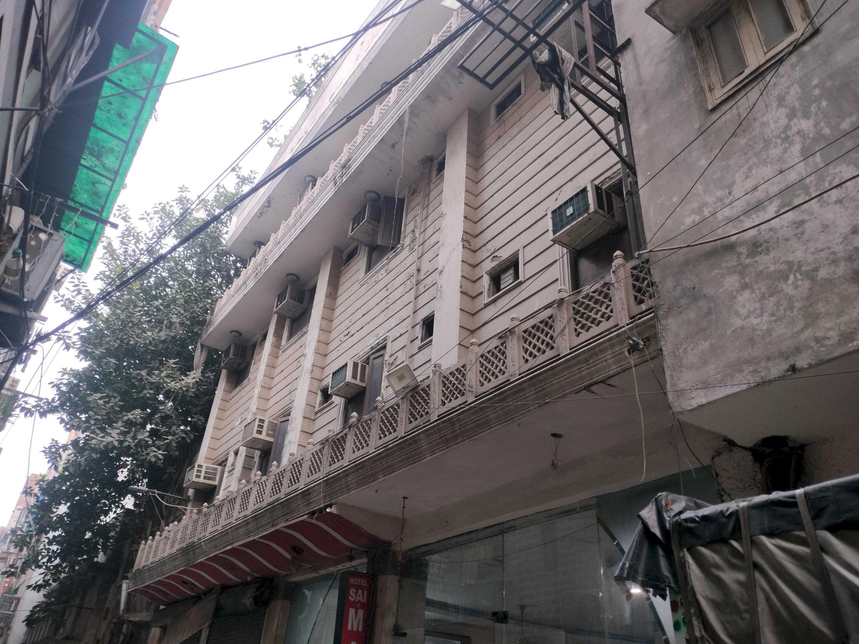 A multi-story building with balconies, air conditioning units, and a visible sign indicating a hotel.