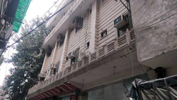 A multi-story building with balconies, air conditioning units, and a visible sign indicating a hotel.