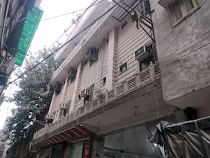 A multi-story building with balconies, air conditioning units, and a visible sign indicating a hotel.