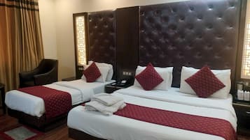 A hotel room with two beds, a dark headboard, and a chair.