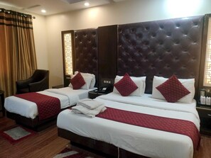 A hotel room with two beds, a dark headboard, and a chair.