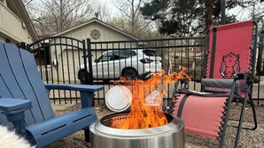 A metal stove with flames, a blue chair, and a red chair with a logo. - Executive King Bungalow on Mount Sequoyah (Fayetteville)