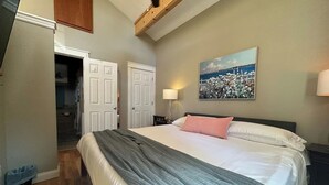 A bedroom with a bed, a nightstand, a lamp, and a painting on the wall. - Executive King Bungalow on Mount Sequoyah (Fayetteville)