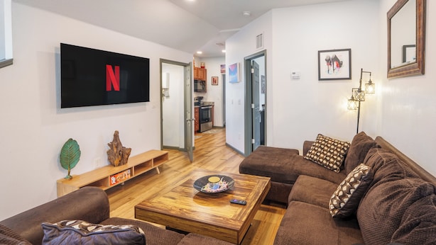 A modern living room with a flat-screen TV, a wooden coffee table, and a brown sofa. - Stylish & Quiet 3BD Sleeps 8 / Near Stadium & DT (Jacksonville)