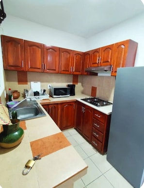 A kitchen with wooden cabinets, a microwave, a stove, and a sink.