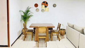 A dining area with a wooden table and chairs, a potted plant, and a sofa. - Apartment in the heart of Oaxaca (Oaxaca de Juárez)