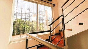 A staircase with metal railings leading to a landing. A window with metal bars is visible, and a painting hangs above the window. - Apartment in the heart of Oaxaca (Oaxaca de Juárez)