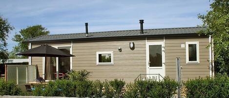 A single-story mobile home with a front porch, a small attached garage, and a fenced yard.