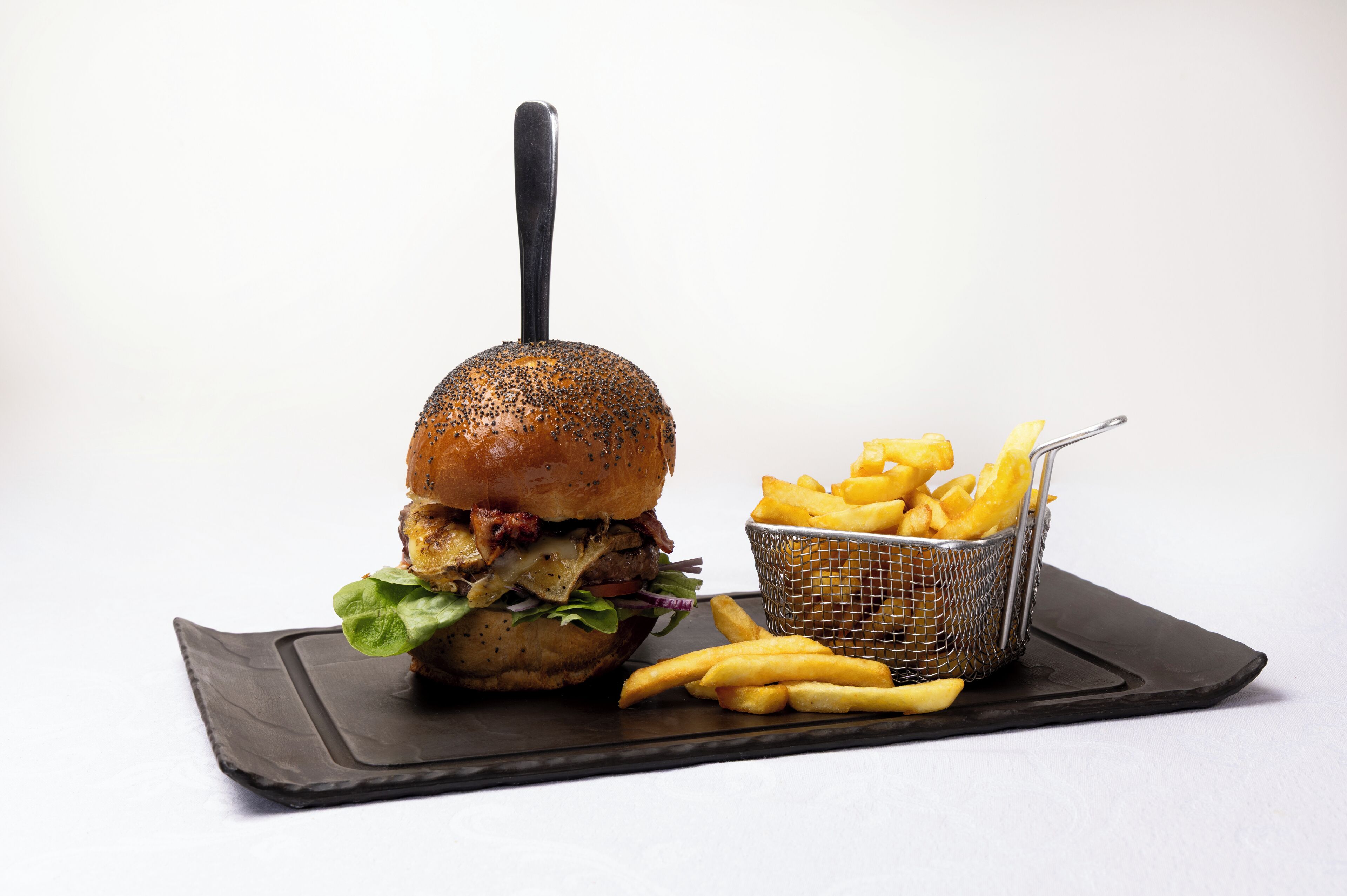 A burger with fries on a black slate plate.