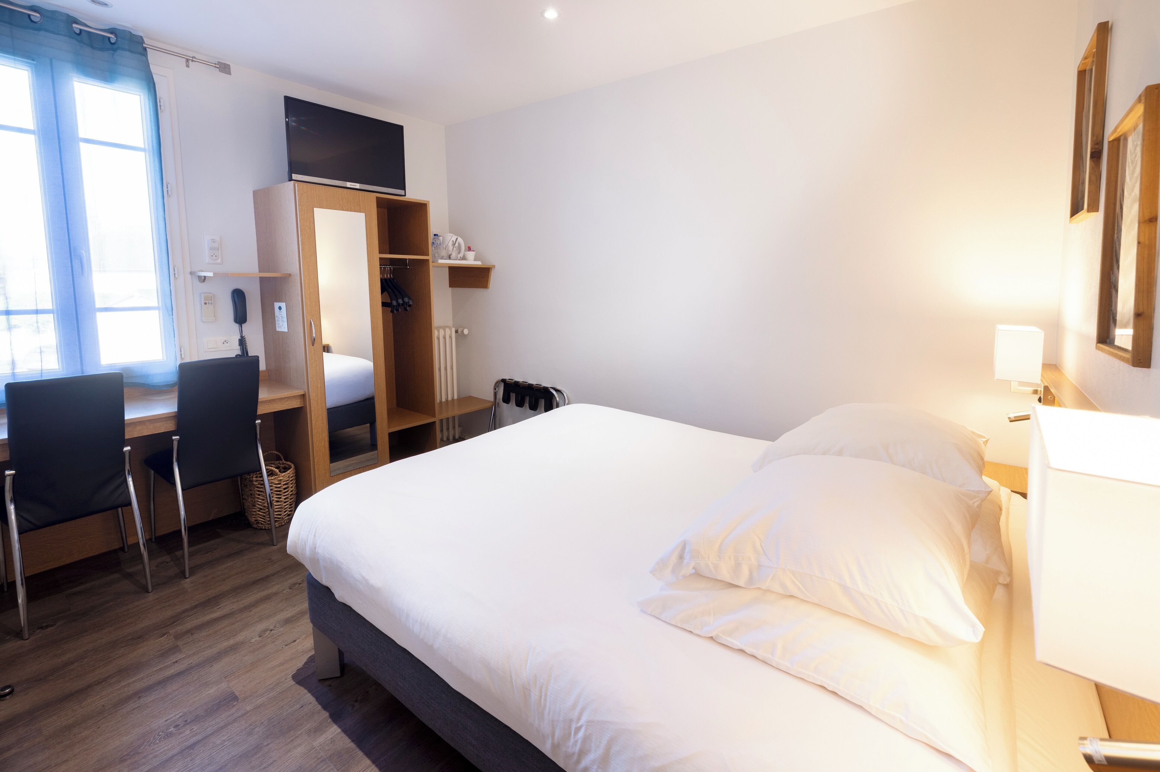 Habitación de hotel con cama, escritorio, sillas y armario.
