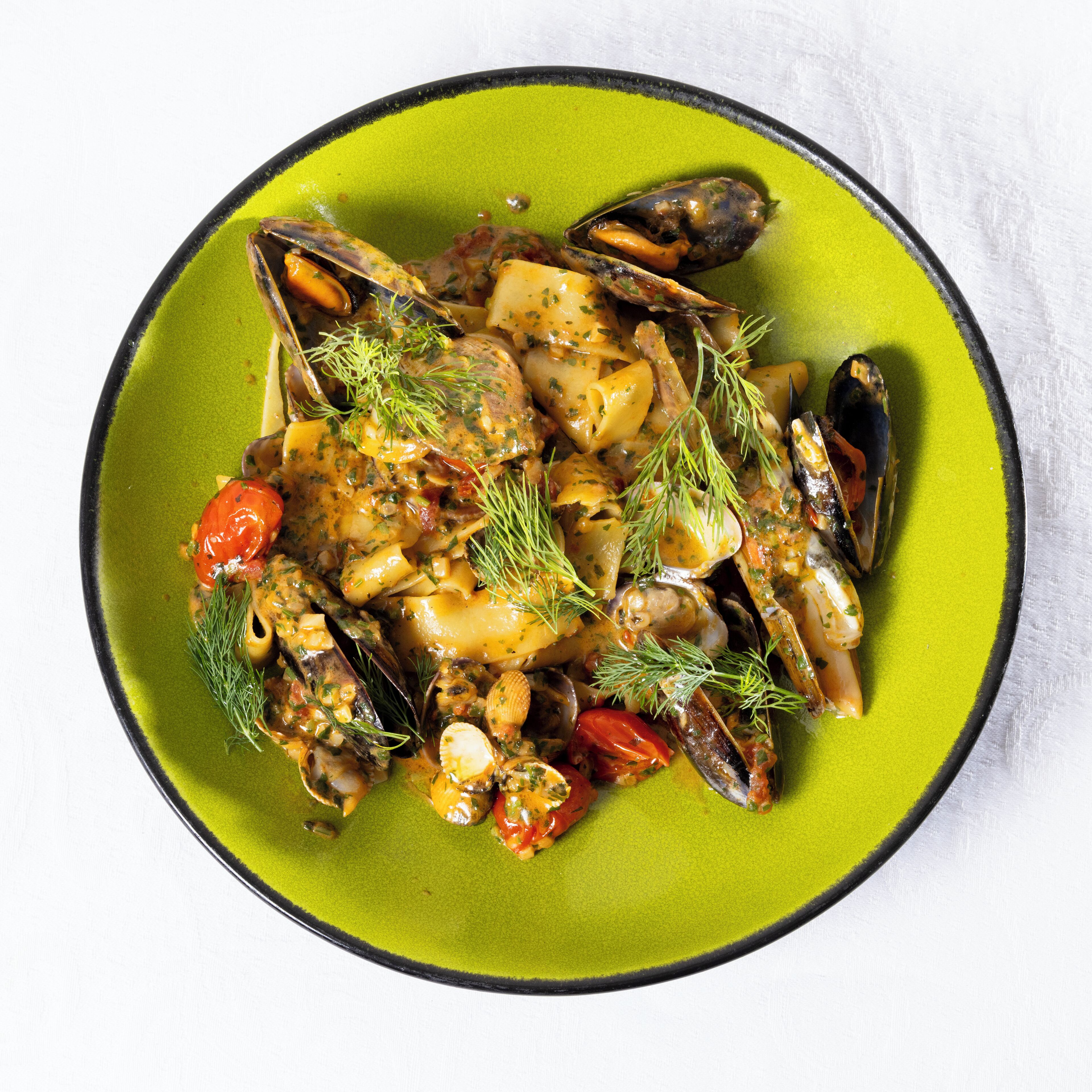 A plate of seafood stew with mussels, potatoes, and herbs.
