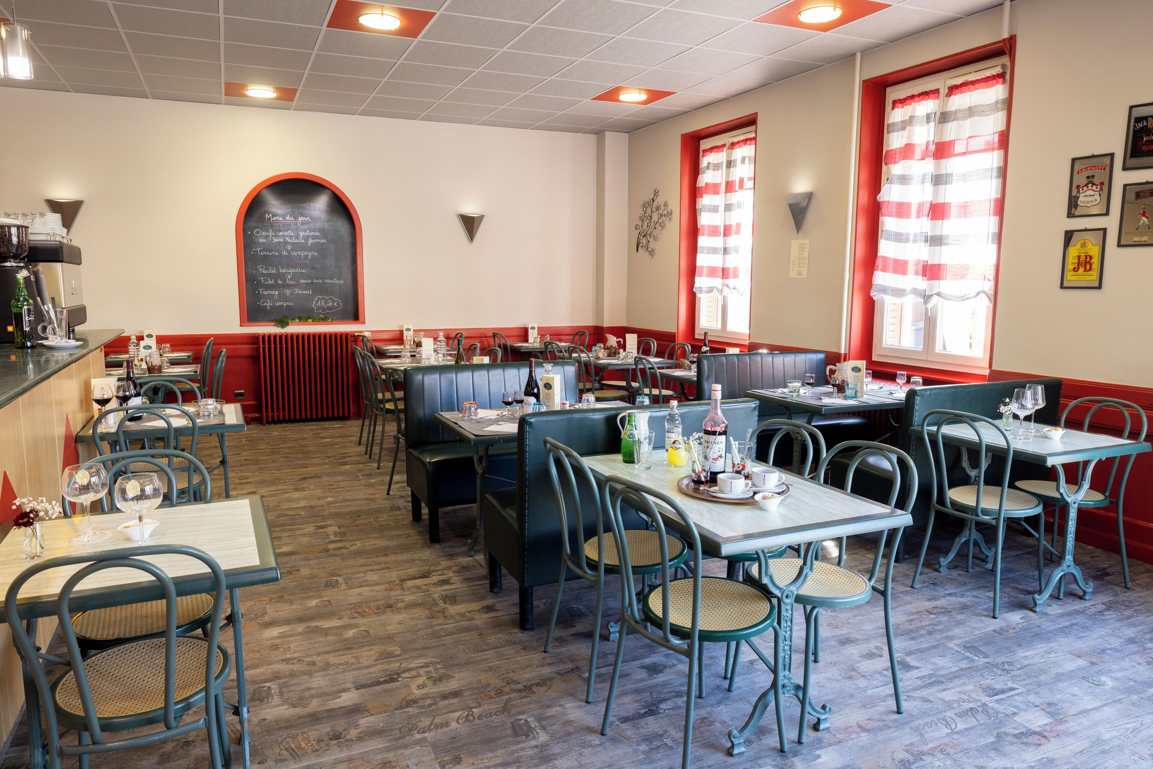 Un restaurante con cabinas y mesas, un menú en una pizarra y cortinas a rayas rojas y blancas.