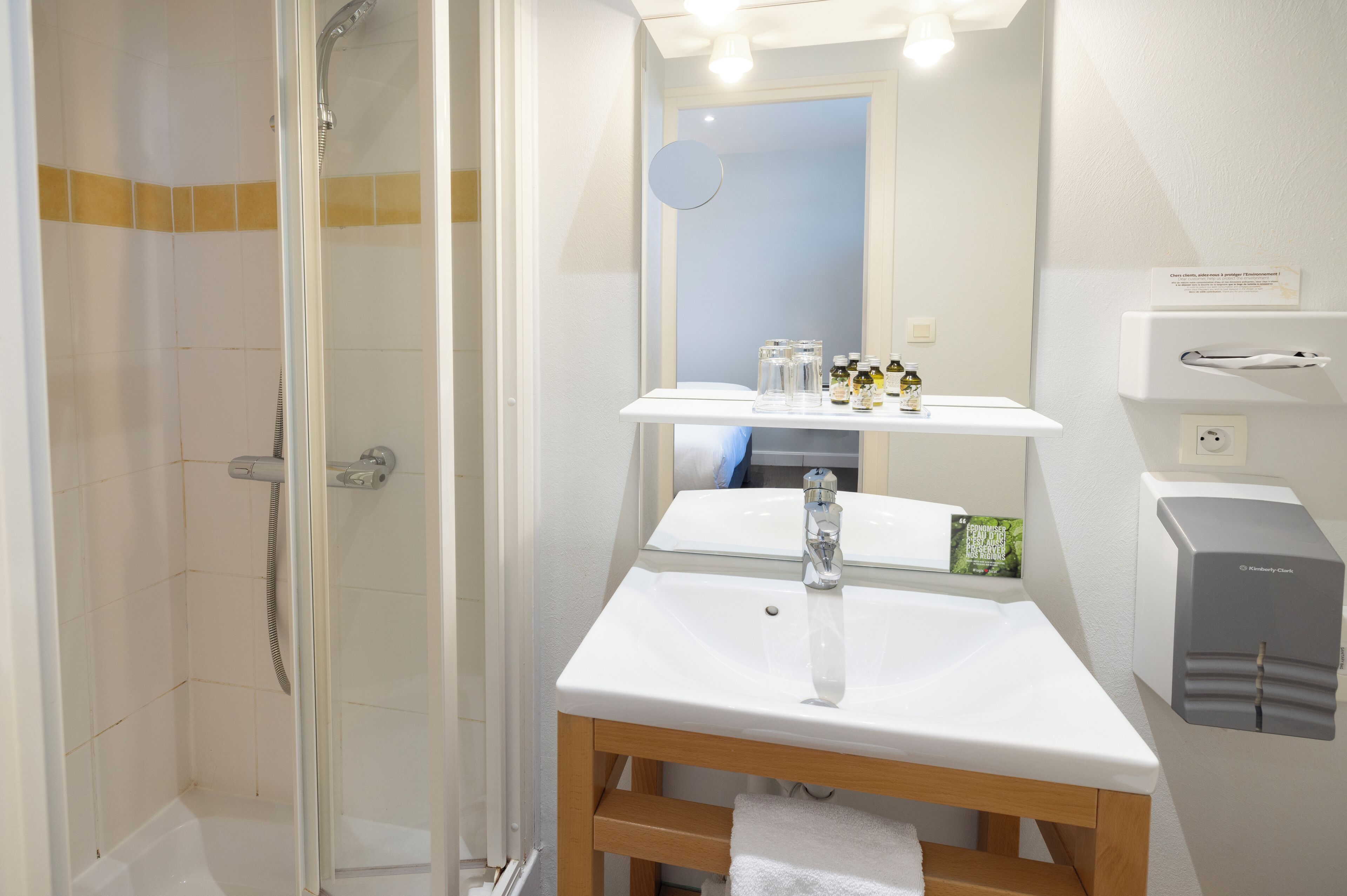 Ein Badezimmer mit Dusche, Waschbecken, Spiegel und Seifenspender.