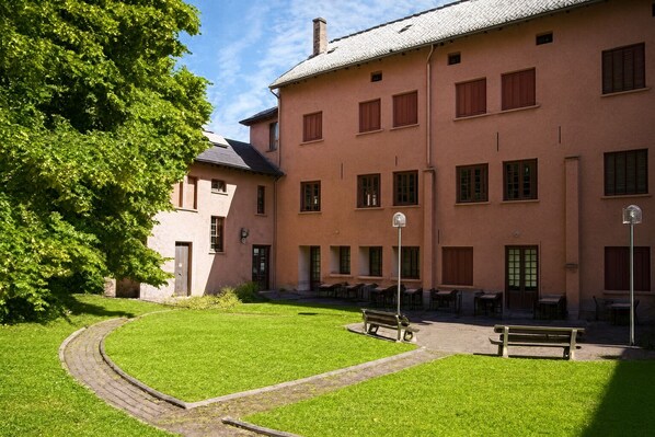 A building with a courtyard, outdoor seating, and a pathway. - La Citadelle de Conflans (Albertville)