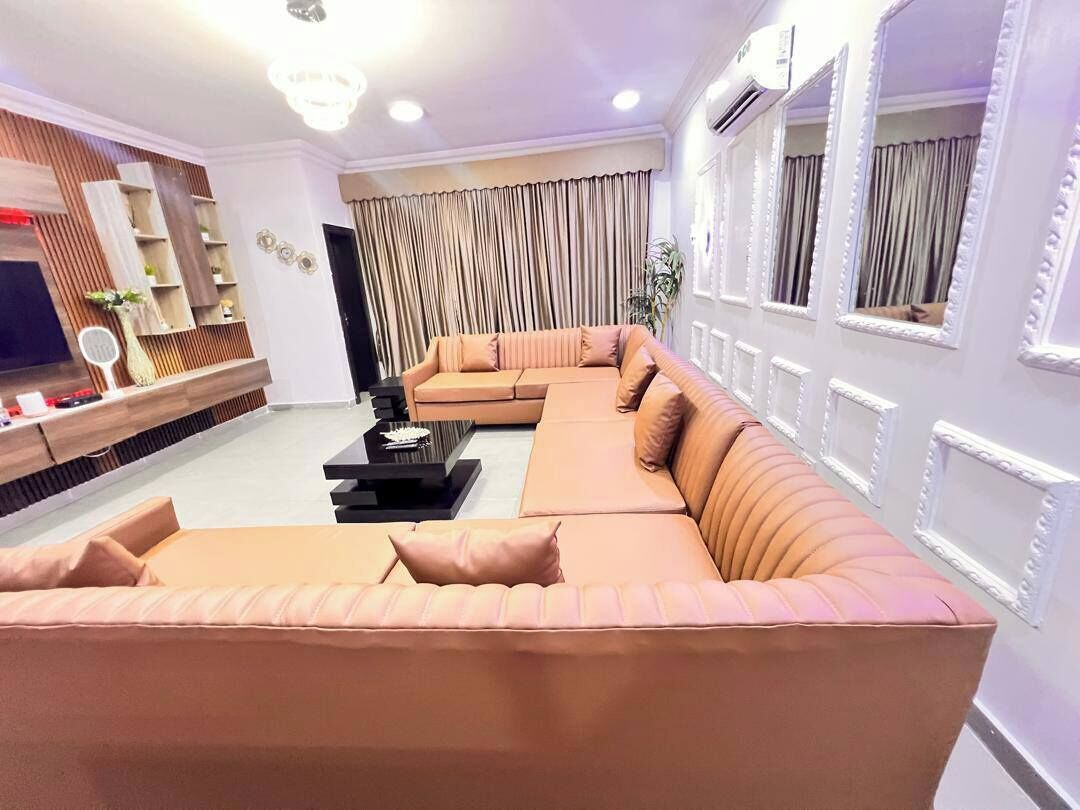 Uma sala de estar moderna com um sofá seccional, uma TV de tela plana e um aparador decorativo.