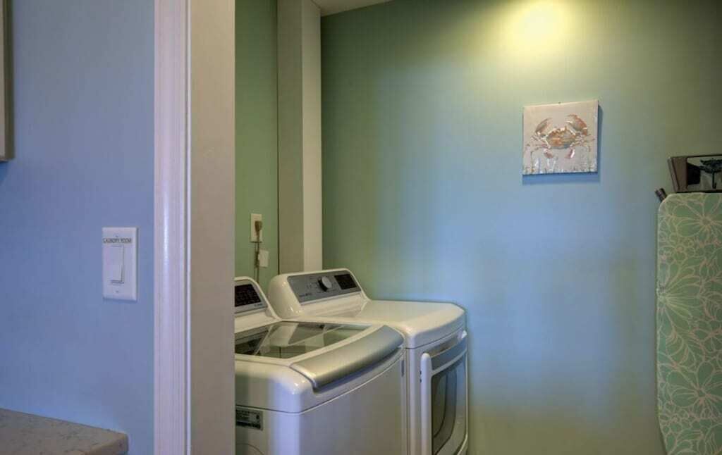 A laundry area with two front-loading washing machines, a light switch, and a framed artwork on the wall.