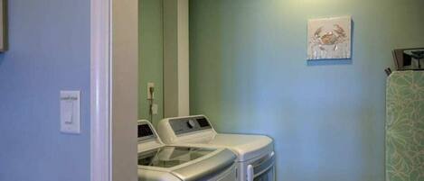 A laundry area with two front-loading washing machines, a light switch, and a framed artwork on the wall.