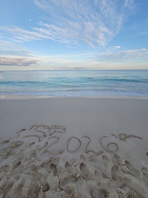 Una playa con huellas y el año '2020' escrito en la arena.