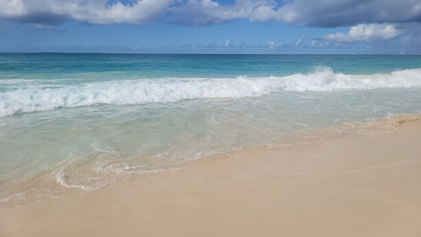 A beach with clear turquoise water and white waves.