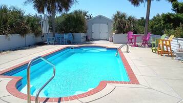 Una piscina rectangular con una escalera metálica, rodeada por una solana de hormigón.