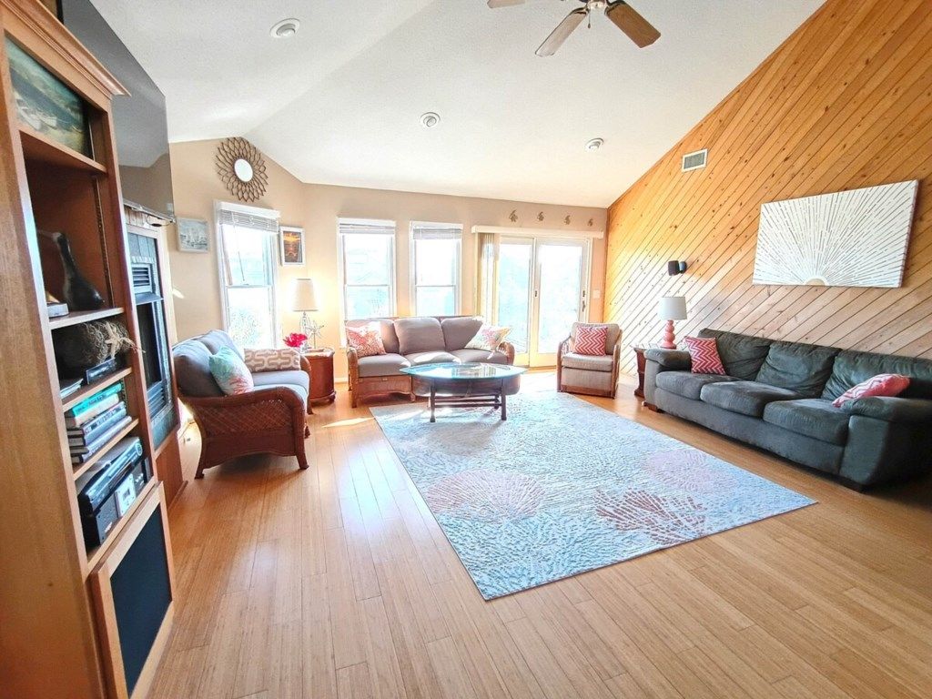 A living room with a fireplace, a bookshelf, and a ceiling fan.