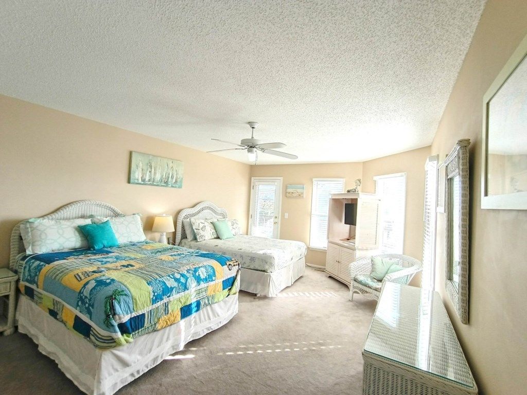 Ein Schlafzimmer mit Bett, Nachttisch, Sessel, Kommode und Deckenventilator.