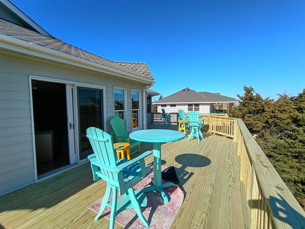 A wooden deck with outdoor furniture and a sliding glass door leading to a covered patio area.