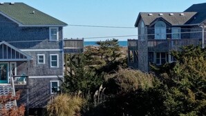 A coastal residential area with houses, a wooden deck, and a view of the ocean. - Oceanview/Elevator/Pool/Hot tub/Steps to beach (Rodanthe)
