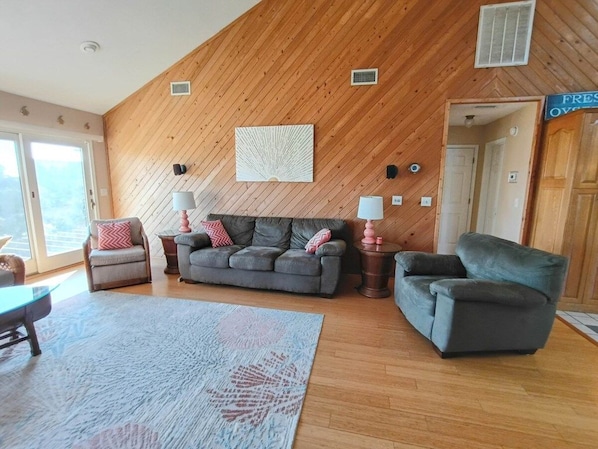 A spacious living area with a wooden ceiling, a sofa set, a coffee table, and a rug. - Oceanview/Elevator/Pool/Hot tub/Steps to beach (Rodanthe)