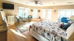 A bedroom with a bed, a television, a ceiling fan, and a window with blinds. - Oceanview/Elevator/Pool/Hot tub/Steps to beach (Rodanthe)
