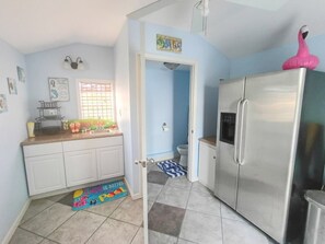 A kitchen with a stainless steel refrigerator, a window with a view, and a colorful rug on the floor.