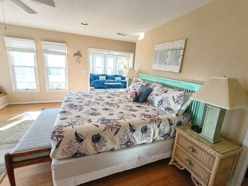 A bedroom with a bed, a nightstand, a lamp, and a window.
