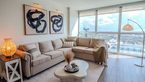 Un salon moderne avec une grande fenêtre, un canapé, une table basse et une lampe.