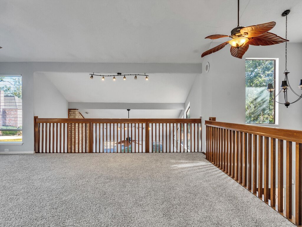 A spacious room with a high ceiling, a wooden railing, and a view of a building outside.