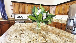 A kitchen with wooden cabinets, a granite countertop, and a sign that reads "Kitchen". - The Grove. Blackfoot. Spacious 4BR. Sleeps 16+  Retreat By Yellowstone (Blackfoot)