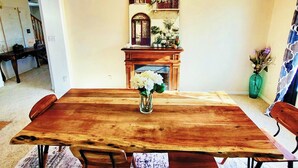 A dining room with a wooden table, chairs, a chandelier, a fireplace, and a decorative wall piece. - The Grove. Blackfoot. Spacious 4BR. Sleeps 16+  Retreat By Yellowstone (Blackfoot)